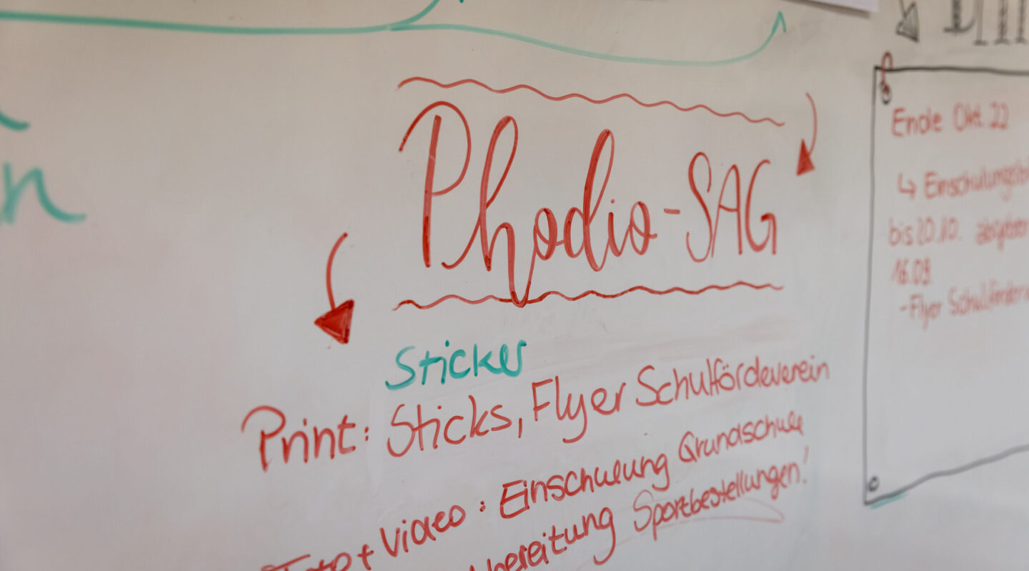 Auf einem Whiteboard steht Phodio SAG und Pfeile.