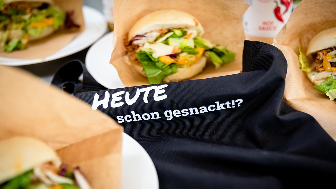 Bao Burger in Papierverpackungen stehen auf einem schwarzen Stoff.